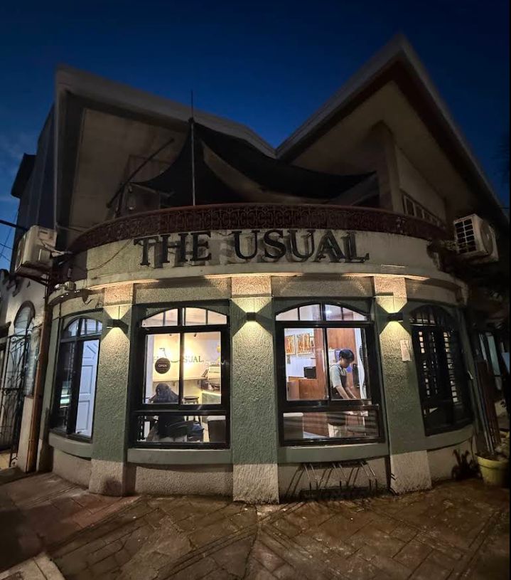 The Usual Coffee storefront at night, with warm light glowing through the windows